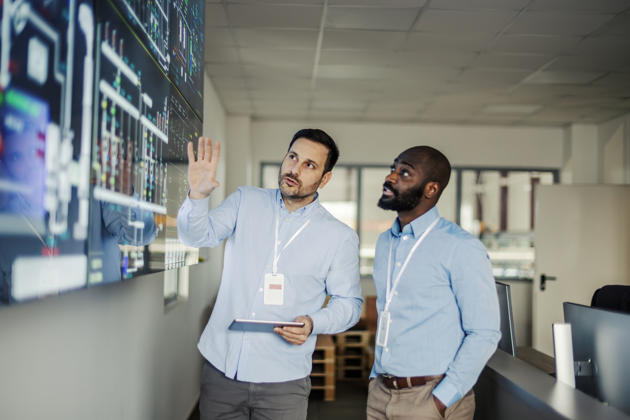 Security advisor briefing a colleague at a monitoring wall, representing CISO advisory services